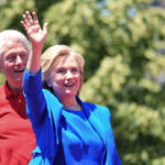 NOW: Clintons Finally Face Epstein Questions Hillary Clinton waving at an outdoor event with Bill Clinton in the background