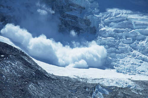 An avalanche cascading down a glacier in a mountainous region