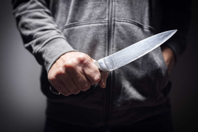 shutterstock_748895263.jpg A person holding a knife in a threatening manner