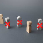 Wooden figures representing people with red crosses indicating exclusion