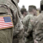 U.S. soldiers in camouflage uniforms with American flag patch.