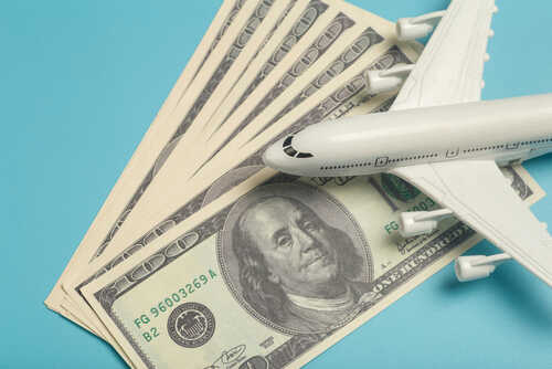 shutterstock_2006302157.jpg A model airplane placed on top of dollar bills