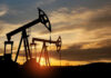 Oil pump jacks silhouetted against sunrise sky