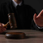 Court SLAMS Trump Delay Judge holding gavel, hand raised in courtroom.