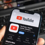 Hand holding phone with YouTube app open.