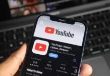 Hand holding phone with YouTube app open.