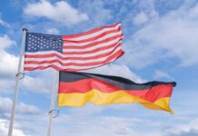 Flags of the United States and Germany waving against a blue sky