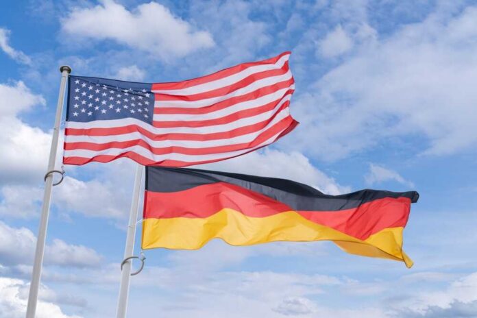 Flags of the United States and Germany waving against a blue sky