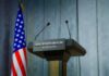 Press podium with the White House sign and an American flag in the background