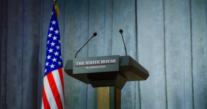 Press podium with the White House sign and an American flag in the background