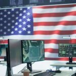A command center with multiple computer monitors and an American flag in the background