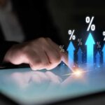 A hand touching a tablet screen with upward arrows and percentage symbols