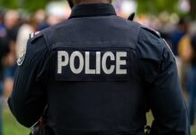 Back view of a police officer wearing a uniform with 'POLICE' displayed