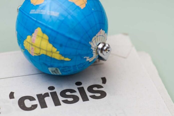 A small globe resting on a newspaper with the word 'crisis'