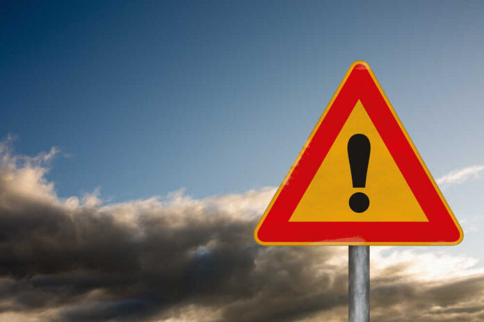 shutterstock_383634874.jpg A triangular warning sign with an exclamation mark against a cloudy sky