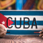 A decorative Cuban license plate with a maraca and a bundle of cigars