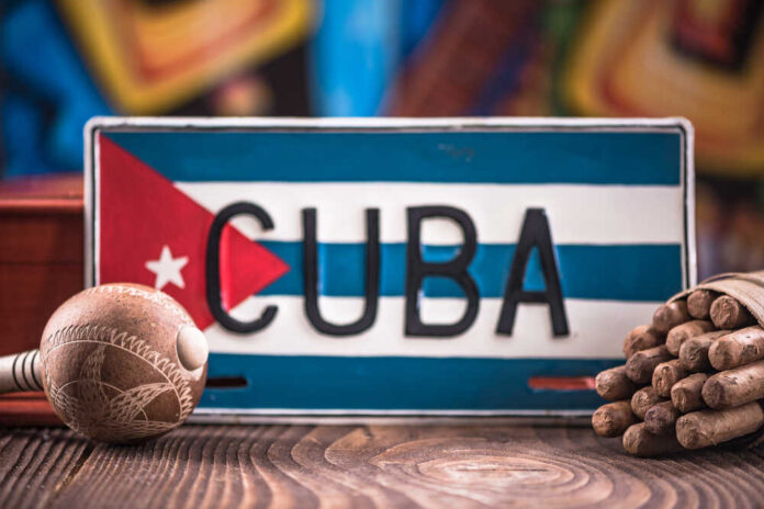A decorative Cuban license plate with a maraca and a bundle of cigars