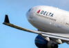 Delta airplane in flight with blue sky background.