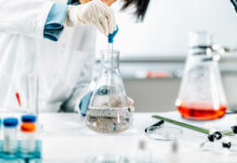 Scientist in a lab using a pipette to transfer liquid into a flask