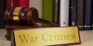 A wooden gavel next to a nameplate reading 'War Crimes'