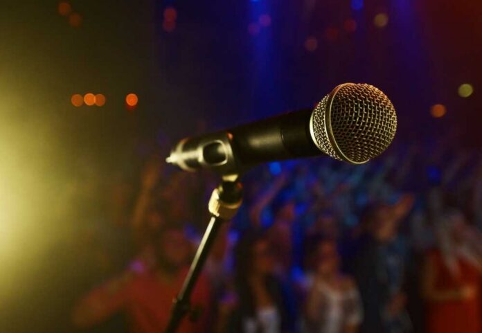 Close-up of a microphone in front of a blurred audience at a concert