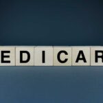Wooden blocks spelling out MEDICARE on a dark background
