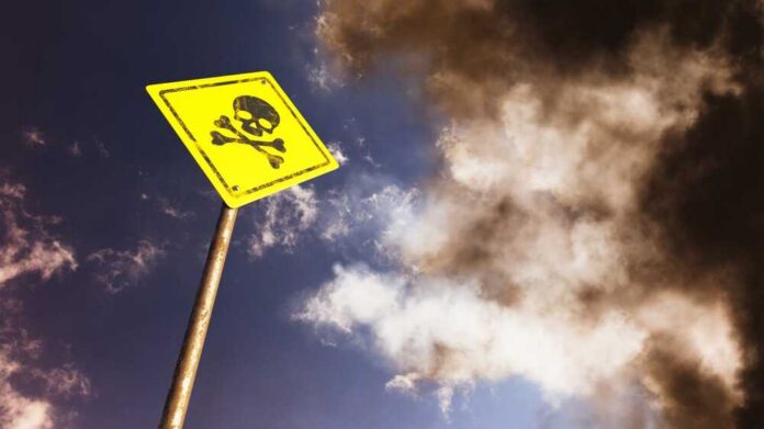A yellow warning sign with a skull and crossbones against a cloudy sky