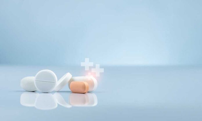 Assorted pills on a reflective surface against a light background