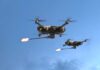 Two military drones firing projectiles in the sky