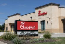 Exterior view of a Chick-fil-A restaurant with a promotional sign
