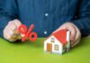Person holding a percentage symbol above a model house