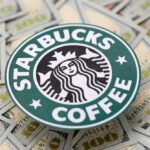 Starbucks coffee logo placed on a background of hundred dollar bills