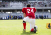 Football player in a red jersey kneeling on the field
