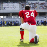 Football player in a red jersey kneeling on the field