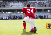 Football player in a red jersey kneeling on the field
