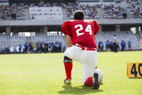 Football player in a red jersey kneeling on the field