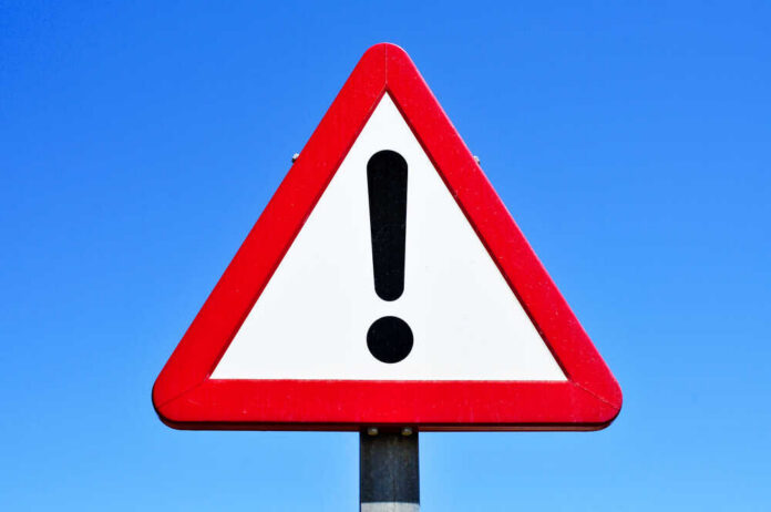 shutterstock_392251453.jpg A triangular warning sign with an exclamation mark against a blue sky