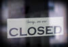 A sign hanging in a window that reads 'Sorry, we are CLOSED'