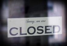 A sign hanging in a window that reads 'Sorry, we are CLOSED'