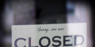 A sign hanging in a window that reads 'Sorry, we are CLOSED'