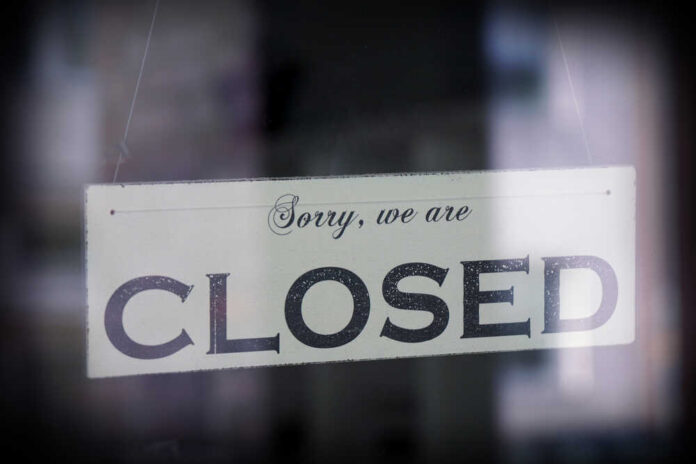 A sign hanging in a window that reads 'Sorry, we are CLOSED'