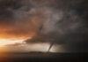 A tornado forming under dark storm clouds at sunset