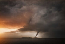 A tornado forming under dark storm clouds at sunset