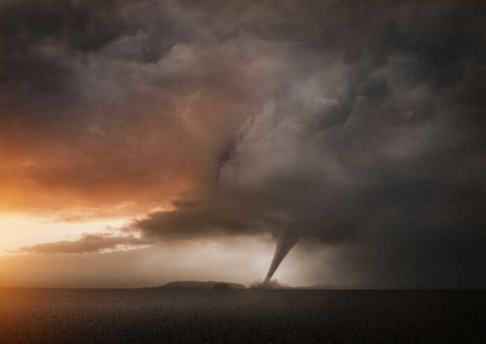 A tornado forming under dark storm clouds at sunset