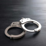 Metal handcuffs on a dark textured surface.