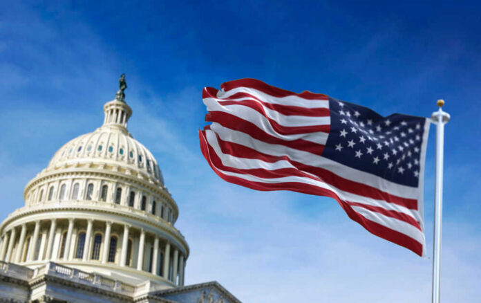 shutterstock_1915477927 U.S. Capitol building with American flag waving.