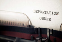 Close-up of a typewriter with a paper showing the words 'DEPORTATION ORDER'