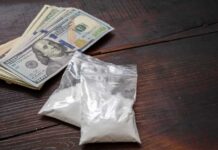Ketamine Plot: Perry’s Assistant Sentenced Bundles of cash next to bags of white powder on a wooden surface