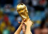 Hands holding the FIFA World Cup trophy aloft in celebration