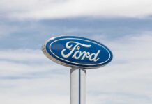 Ford logo displayed on a sign against a cloudy sky